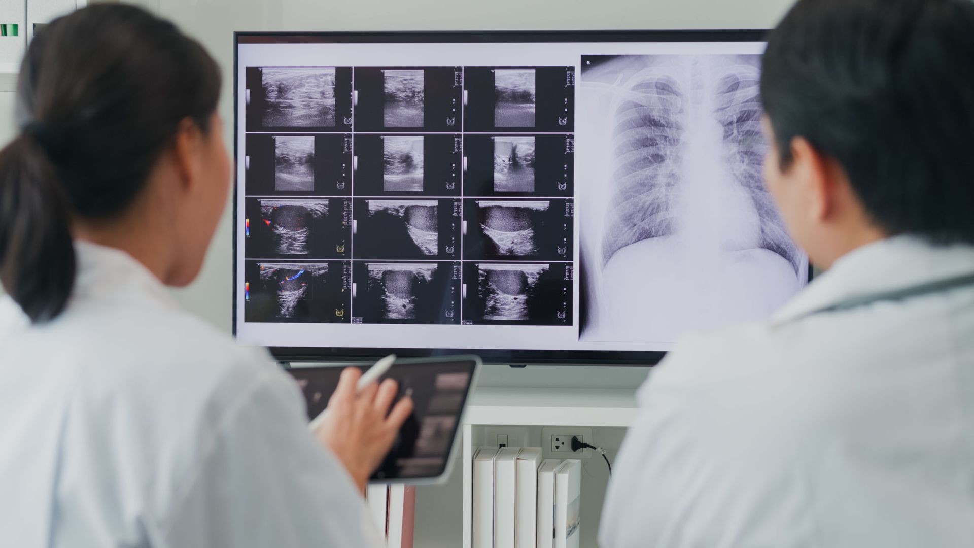 Two medical professionals reviewing ultrasound and X-ray images on a screen.