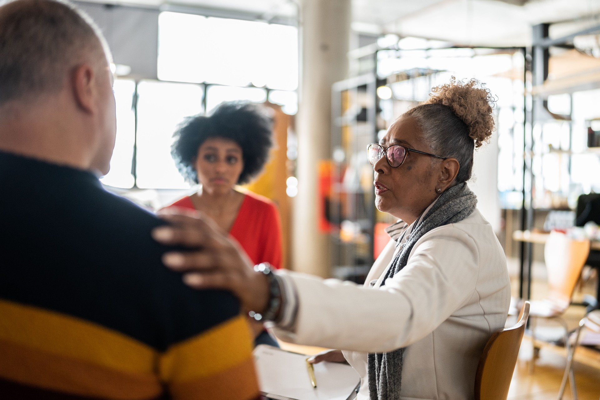 Senior woman comforting a mature man in group therapy at a coworking